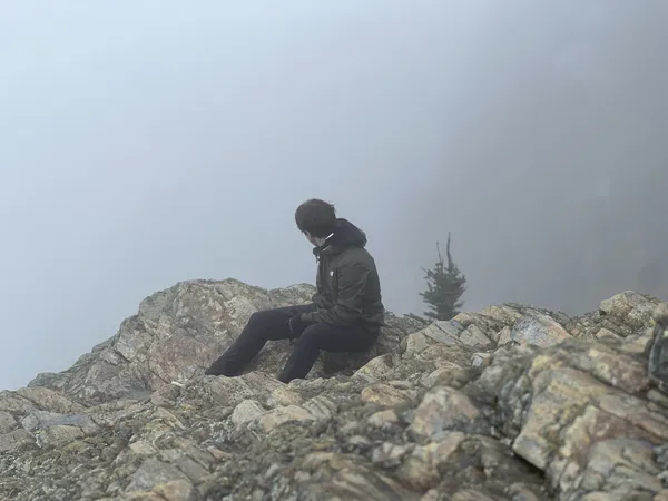 George sitting on a rocky summit in fog
